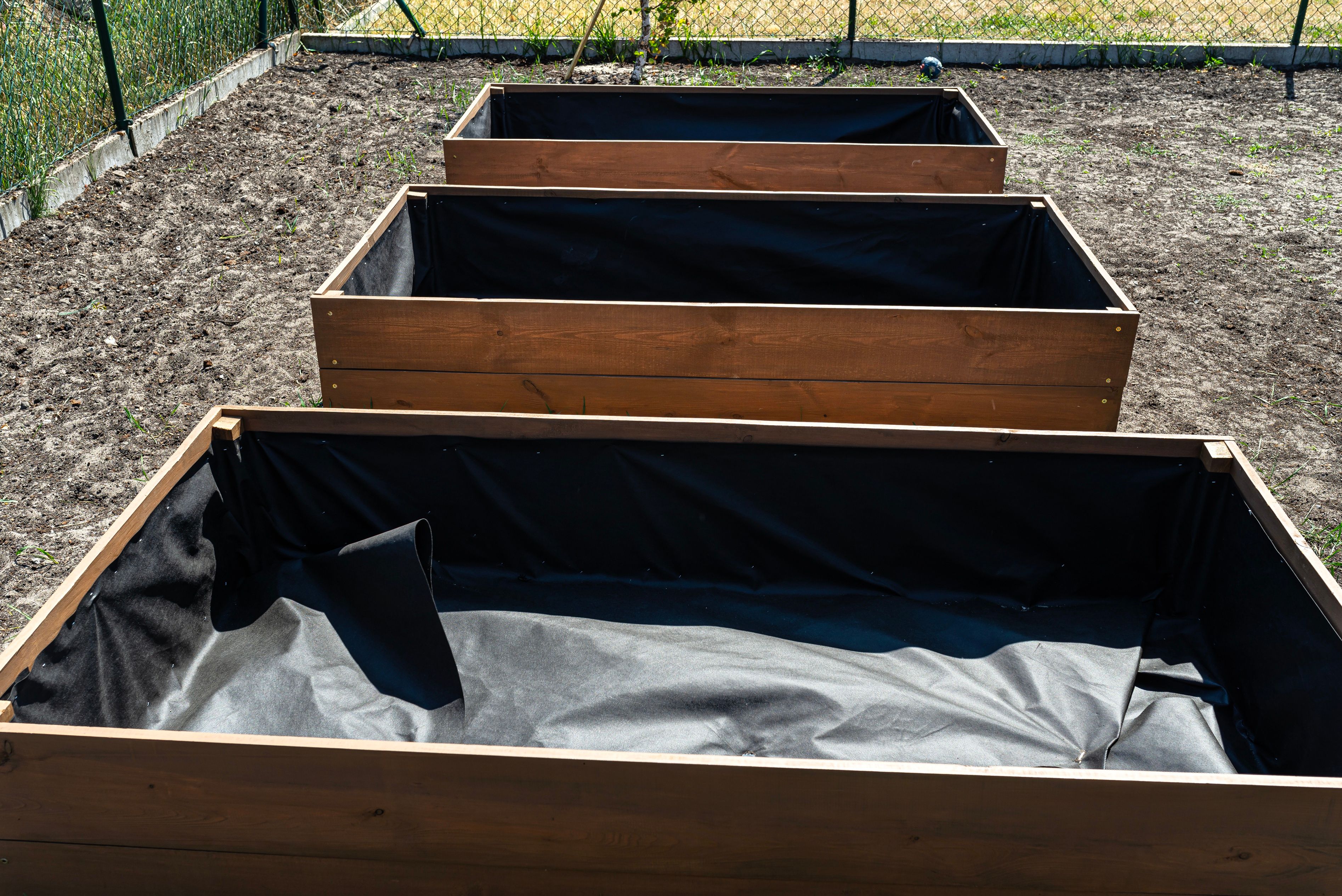 Wooden raised beds for vegetables lined with agrotextile from the inside.