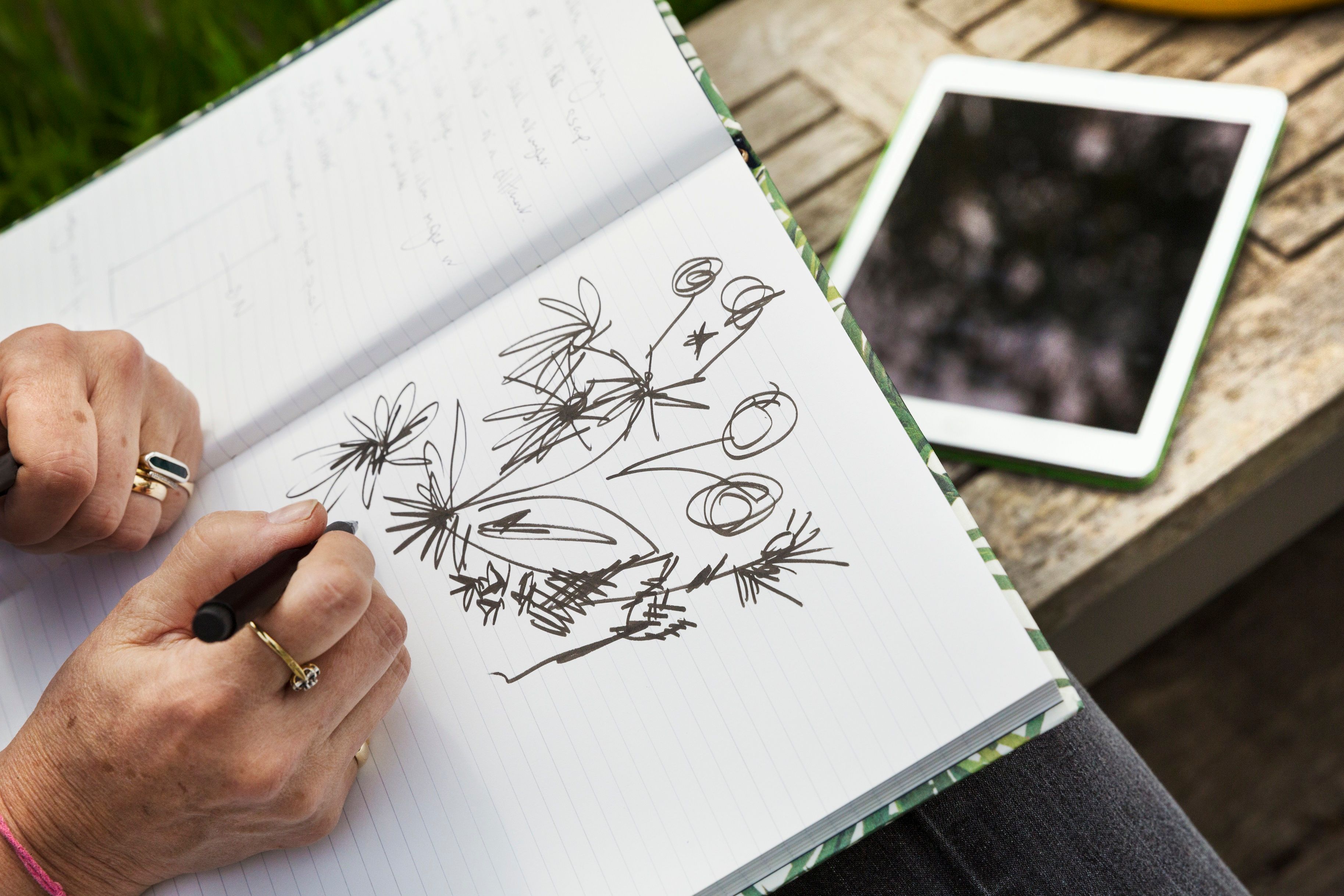 Woman sitting on a bench drawing flowers in a sketchbook